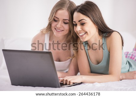 Pajama party. Beautiful young girls in pajamas looking at laptop at home.
