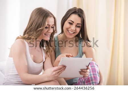 Pajama party. Young beauty girls in pajamas using a tablet  in bed at home.