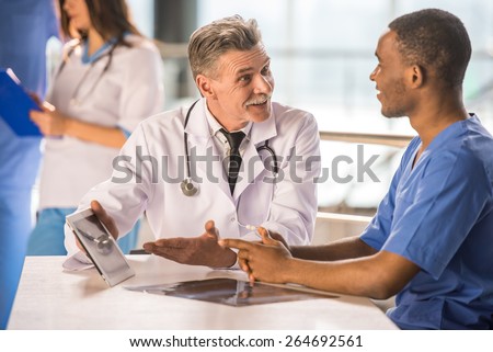 Senior doctor and young doctor talking and using a tablet.