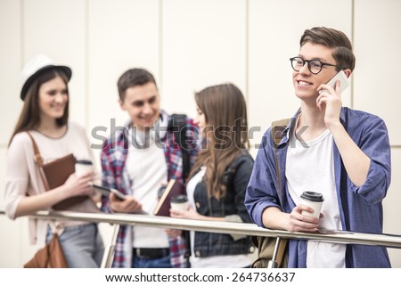 Handsome young student talking on the phone. His classmates in the background.