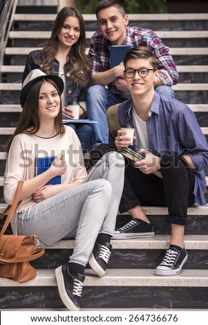 Three young students learning on stairs in college. And looking on camera.