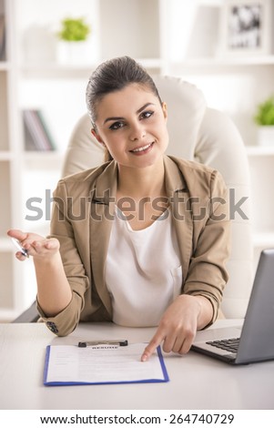 Beauty young businesswoman sitting in office. And looking at camera.