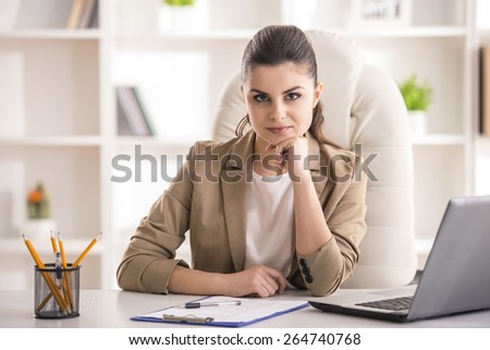 Beauty young businesswoman sitting in office. And looking at camera.