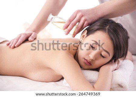 Side view. Beautiful asian woman having massage with spa oil in beauty salon.