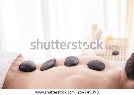 Spa Hot Stone Massage. Spa therapy. Young male Getting Spa Treatment.