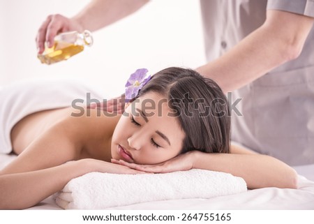 Side view. Beautiful asian woman having massage with spa oil in beauty salon.