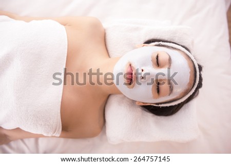 Spa therapy for young asian woman receiving facial mask at beauty salon.