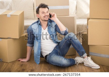 The young happy man calling transport company to move in new house.