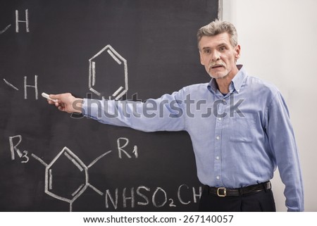 Professor of chemistry writes on the blackboard formula in University.