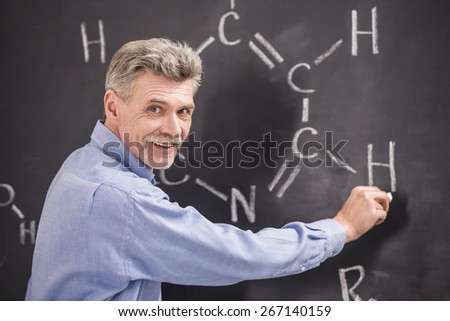Professor of chemistry writes on the blackboard formula in University.