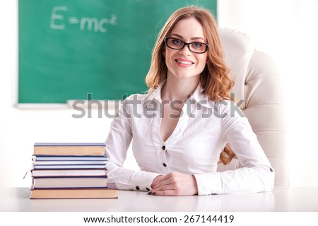 Teacher sitting in the classroom on blackboard background.