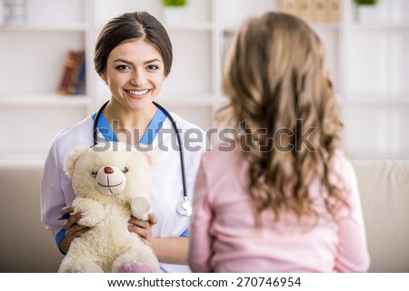 Young smiling female doctor with teddy bear and little girl.