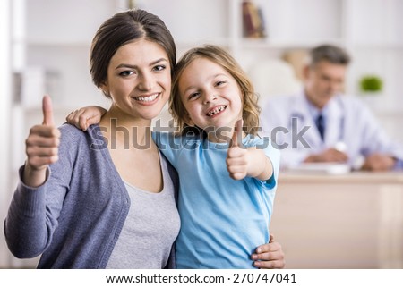 Smiling mother and her little daughter at the doctor. Doctor is sitting on background.