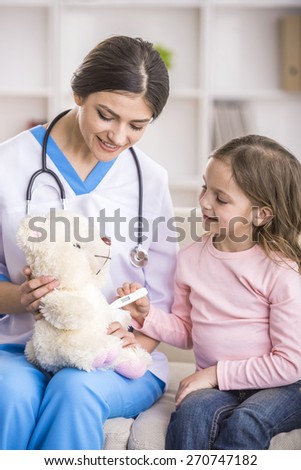 Young smiling female doctor and her little patient  with teddy bear.