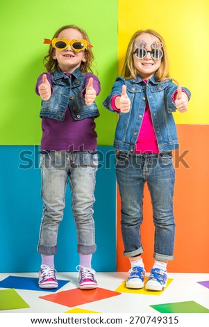 Best friends. Two cute little girls having fun with fun glasses on colorful background.