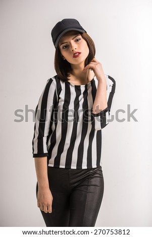 Portrait of young beauty woman in black-white shirt and in cap on grey background.