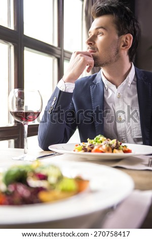 Handsome young businessman eating during a business lunch in restaurant.