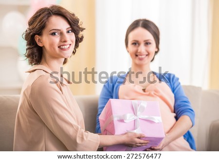 Young woman gives a gift to her pregnant friend.