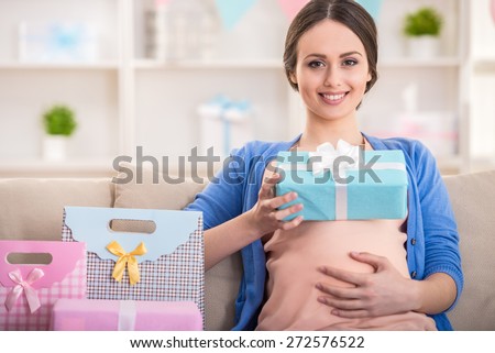 Happy pregnant woman is sitting with presents at a baby shower.
