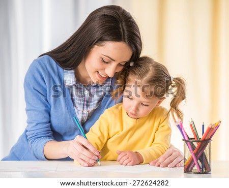 Mother and daughter are having fun while drawing at home.