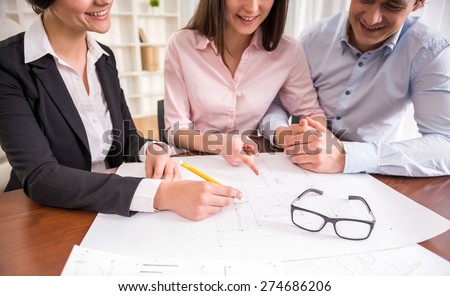 Female realtor showing contract with floor layout in an apartment to a young couple.