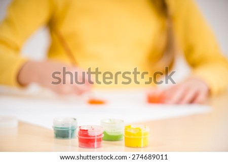Little  girl in yellow  pullover making picture with  gouache paints.