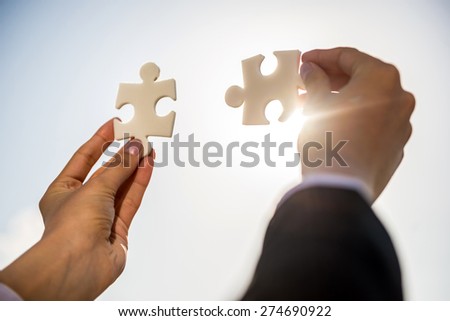 Closeup of business people wanting to put two pieces of puzzle together.