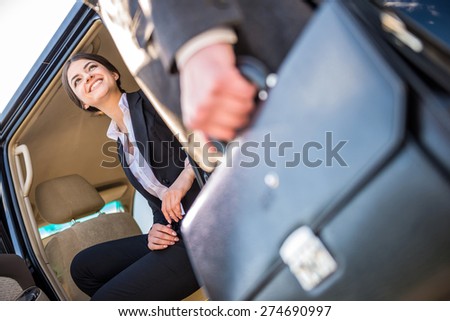 Young beautiful smiling businesswoman in suit sitting in her luxurious car.