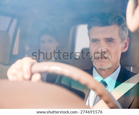 Mature confident successful  businessman  in suit driving his luxurious car.