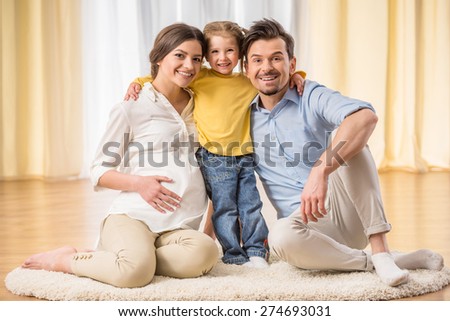Happy family expecting new baby. They are looking at the camera and smiling.