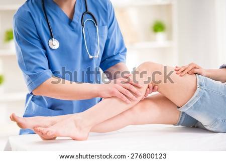 Physiotherapist massaging the  leg of female patient in a physio room.