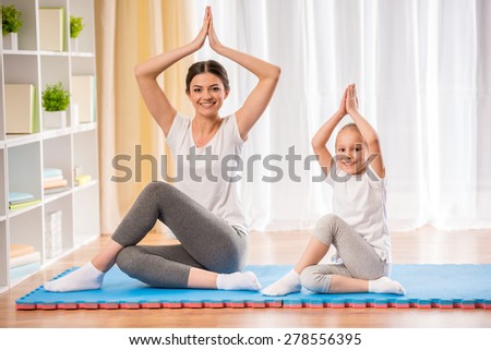 Mother and daughter doing yoga exercises on mat at home.