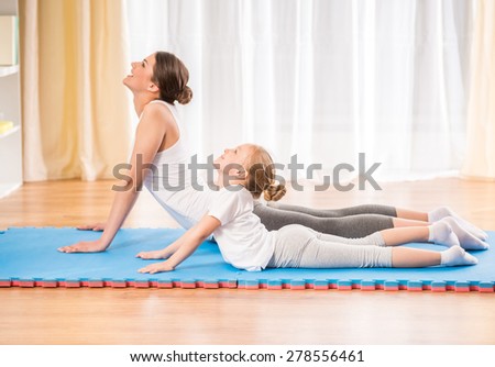 Mother and daughter doing yoga exercises on mat at home.