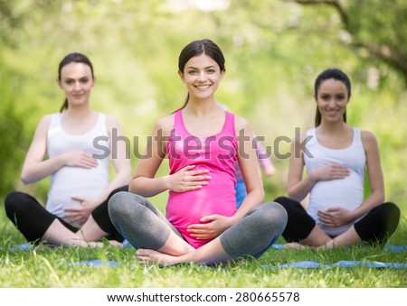 Group of smiling pregnant women doing prenatal yoga.