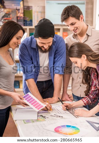 Creative team of designers dressed casual choosing color from swatch at office.