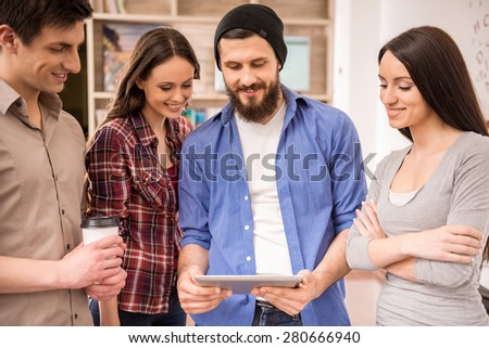Creative group of designers dressed casual looking at digital tablet.