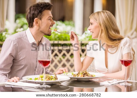 Young smiling couple enjoying the meal in gorgeous restaurant and drinking wine. Woman feeding man.
