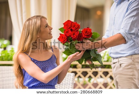 Man surprising his cute girlfriend with flowers on romantic date.
