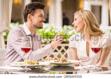 Young smiling couple enjoying the meal in gorgeous restaurant and drinking wine. Man feeding woman.