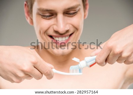 Handsome man cleaning teeth with tooth brush in bathroom.
