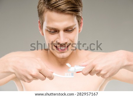 Handsome man cleaning teeth with tooth brush in bathroom.