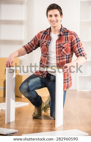 Happy handsome man measuring home furniture with measure tape. Repair concept.