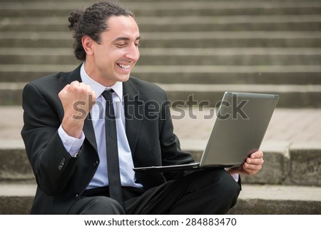 Man in suit sitting at stairs with laptop. Unemployed man looking for job.