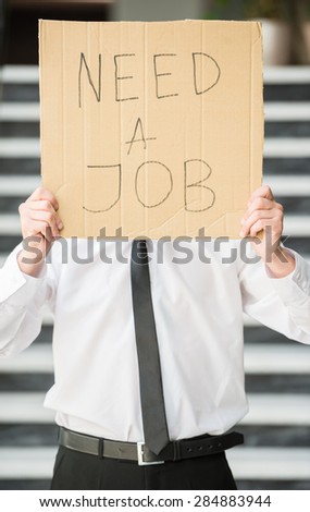 Close-up of man in suit holding sign in hands. Unemployed man looking for job.