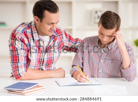Happy father helping his son to do homework.