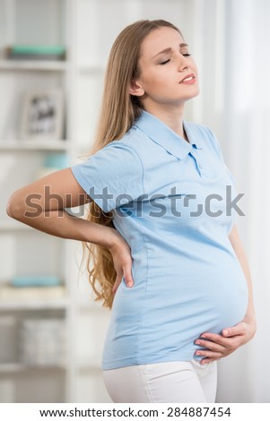 Young pregnant woman suffering from ache at home.