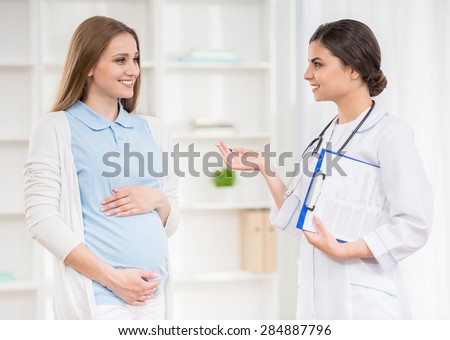 Doctor explaining something to her pregnant patient at clinic.