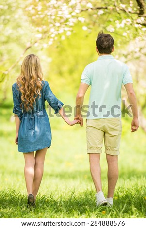 Young beautiful couple dressed casual having fun in summer park.