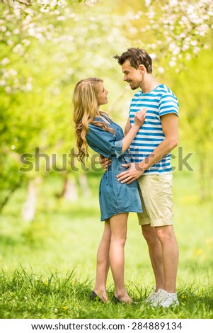 Young beautiful couple dressed casual hugging in summer park.