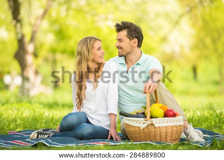 Young beautiful couple having picnic on the lawn in summer park.